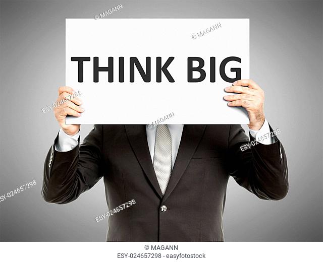 A business man holding a paper in front of his face with the text think big