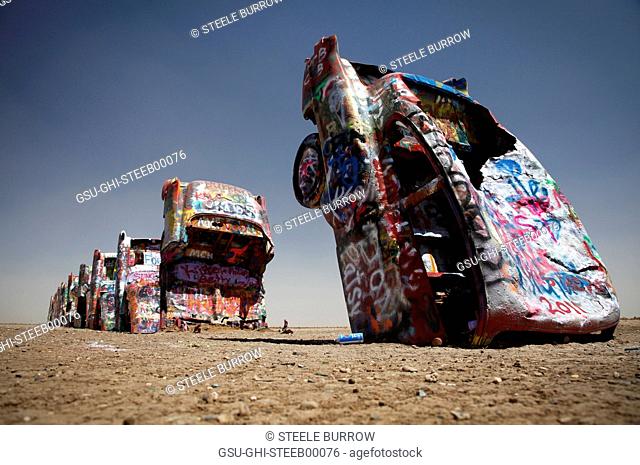 Row of Abandoned Cars Covered in Graffiti Buried in Ground, Texas, USA
