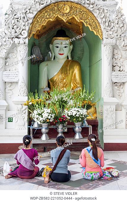Myanmar, Yangon, Shwedagon Pagoda, Women Praying in front of Buddha Statue