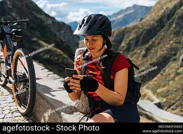 Cyclist wearing helmet using smart phone by bicycle