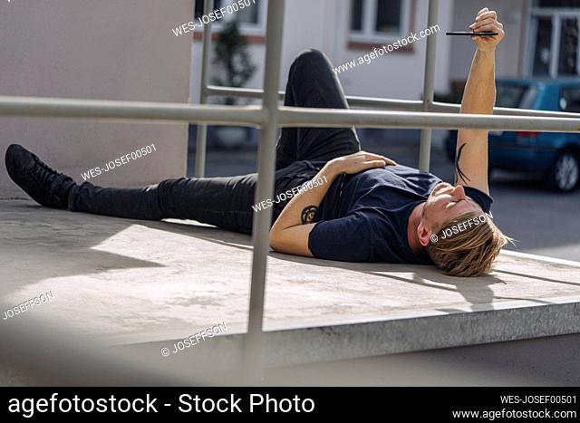 Man lying on a scaffolding using smartphone