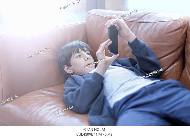 Boy playing with smartphone on sofa