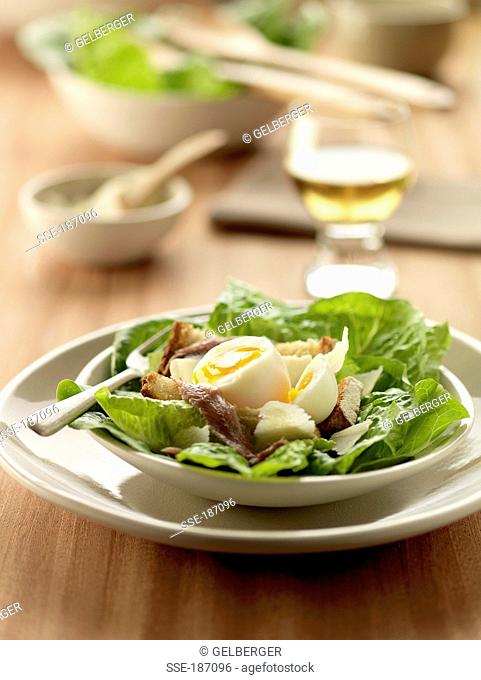 Spinach salad with soft-boiled egg, anchovies and roquefort on bread