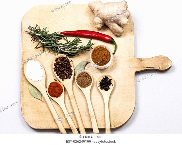 Various colorful spices on isolated wooden cutting board