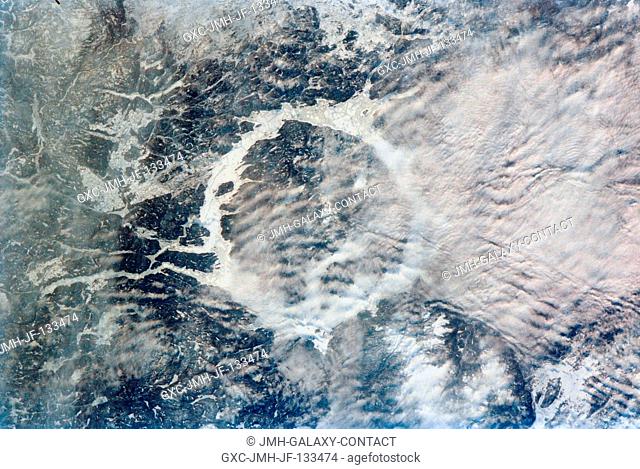 Low clouds (center right) partially obscure a portion of the ice-covered Manicouagan Reservoir located in the Canadian Shield of Quebec Province in eastern...