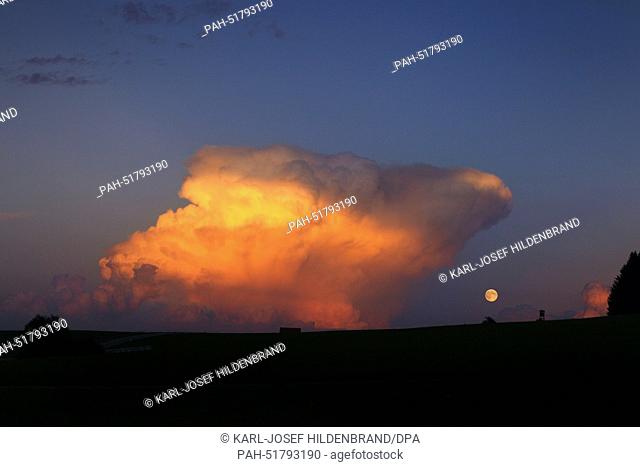 A view of the full moon next to clouds illuminated by the setting sun at the Auerberg near Bernbeuren, Germany, 08 September 2014