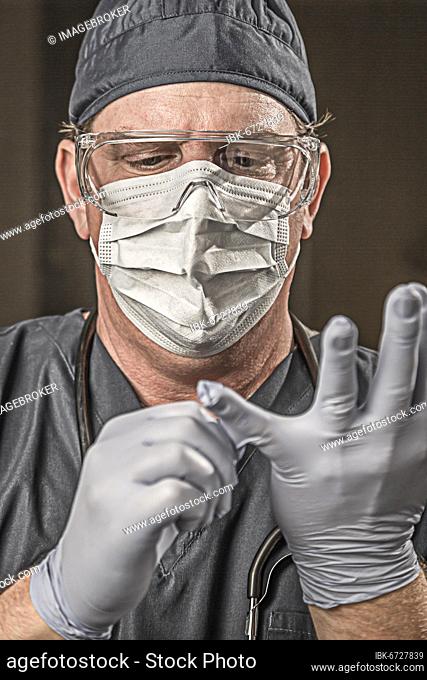 Male doctor or nurse wearing scrubs, protective face mask and goggles