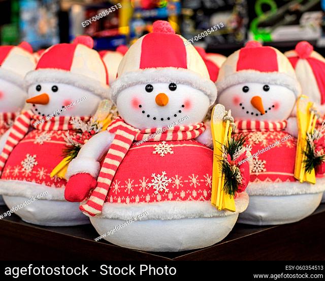 Cute toy snowman in a hat and a pink sweater with skis. New Year decorations, holiday toys. Christmas card with snowmen, close-up