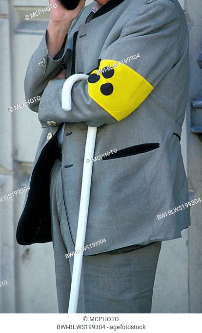 man with white cane and identification armband for the visually impaired