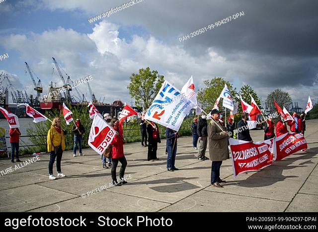 01 May 2020, Hamburg: Participants in a demonstration on the nationwide ""Labour Day"" stand with banners reading ""Solidarisch ist man nicht allein"" (""One is...