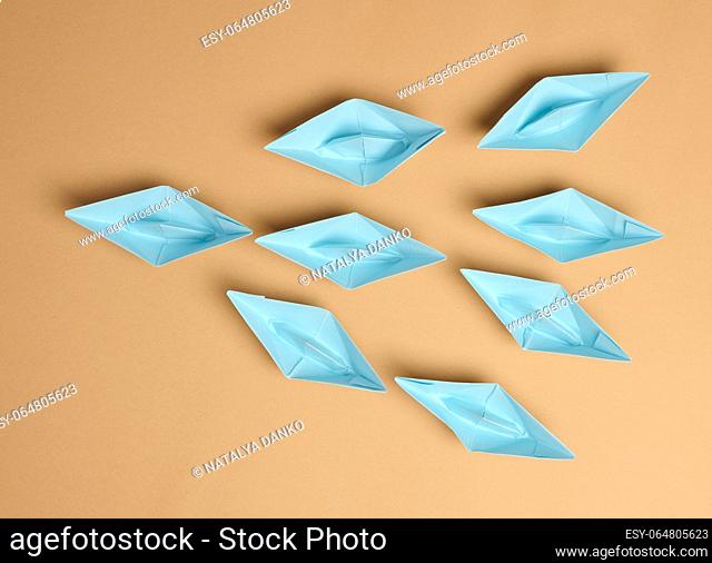 Group of paper boats on a brown background. Concept of a strong leader in a team, manipulation of the masses, following new perspectives