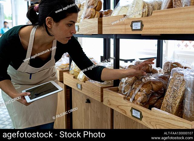 Shot of female Latin-American bakery owner checking prices of merchandise