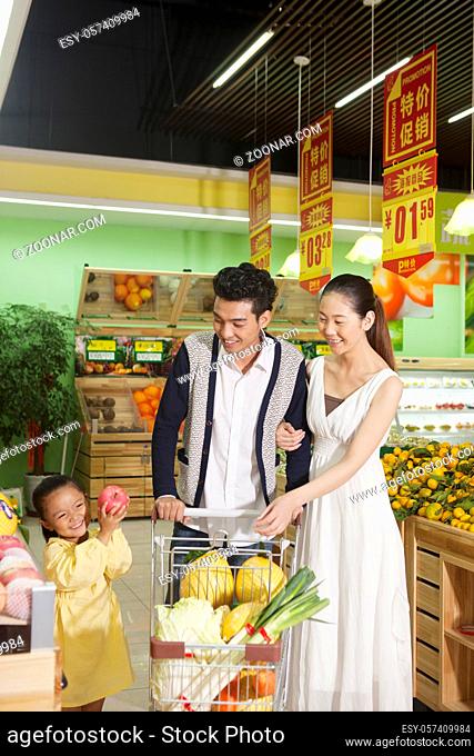A happy family of three in the supermarket shopping high quality photo