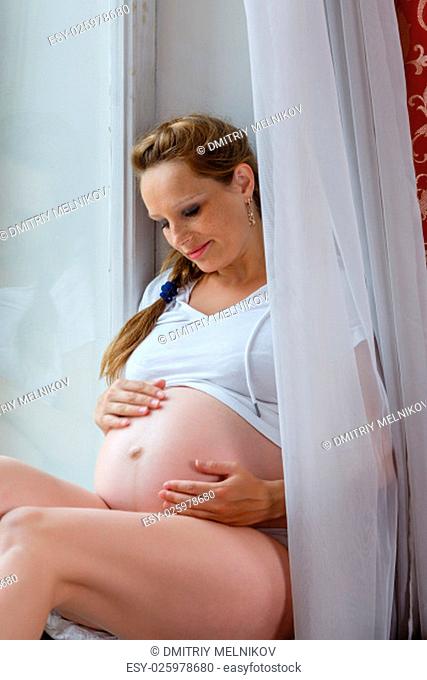 Pregnant woman sits near window in the room