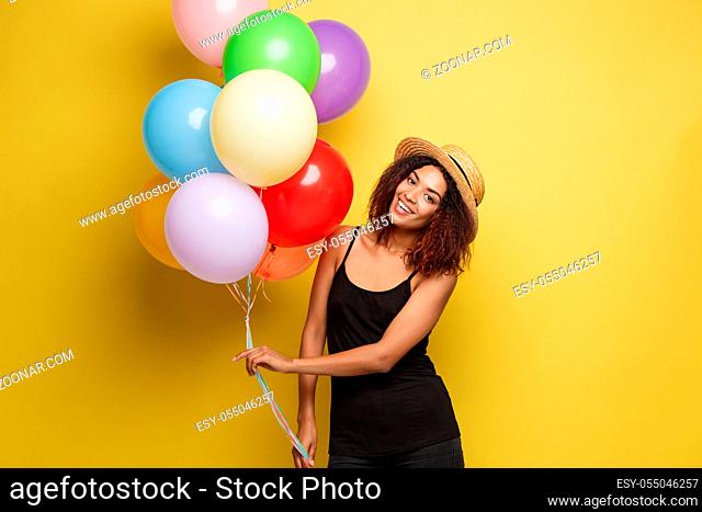 Celebration Concept - Close up Portrait happy young beautiful african woman in black t-shirt smiling with colorful party balloon