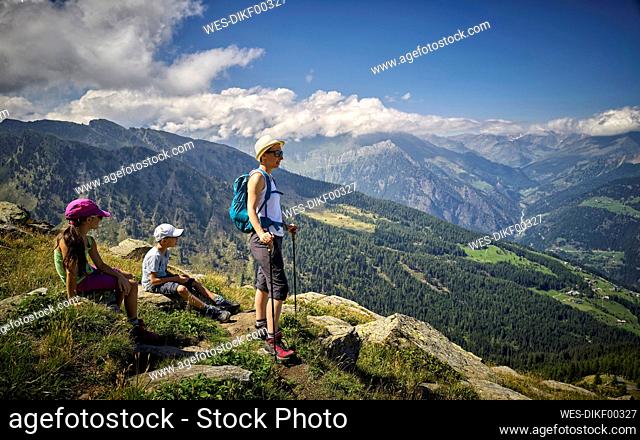 Mother with two children having a break from hiking in alpine scenery, Passeier Valley, South Tyrol, Italy