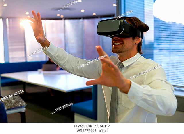 Happy young male executive using virtual reality headset in a modern office