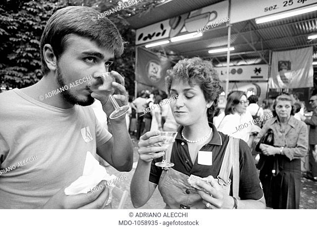 Festa dell'Unità. Young people eating and drinking outdoors at Festa dell'Unità in Parco Sempione. Milan, September 1979