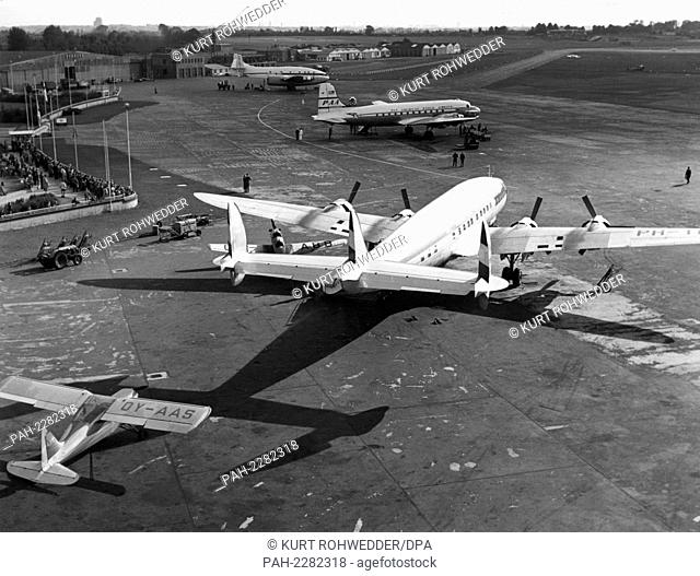 A Lockheed ""Super Constellation"" aircraft of a Dutch airline rolls over the airfield in Hamburg-Fuhlsbuttel in 1953. Front left a Junkers junior from the year...