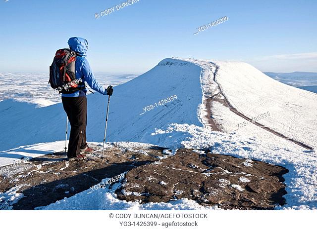 Female hiker viewing Pen Y Fan from Summit of Corn Du in winter, Brecon Beacons national park, Wales
