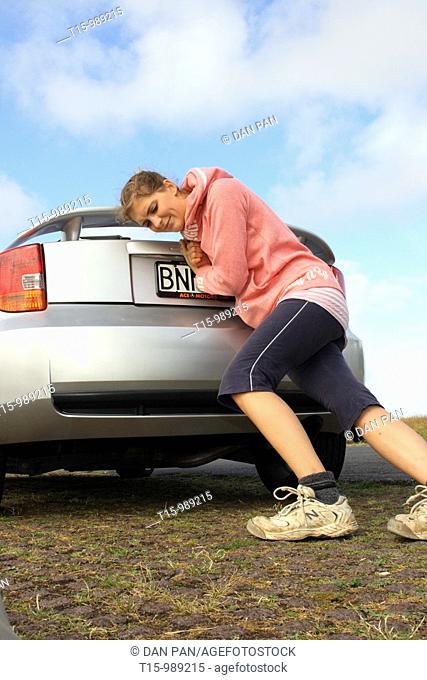 a woman pushing a broken down car