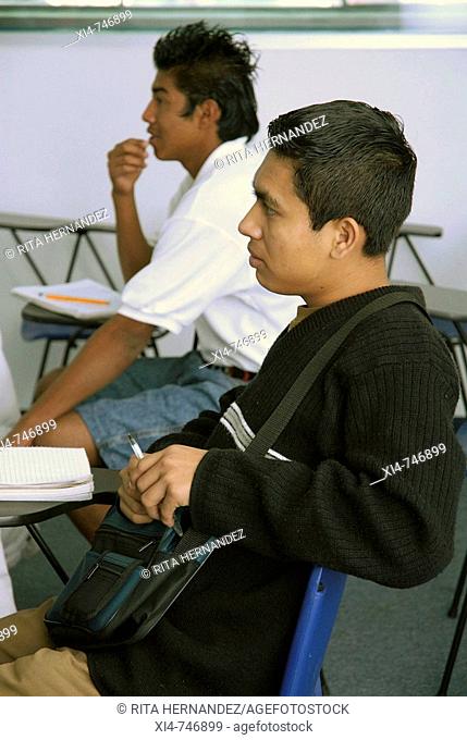 Couple of young males. Seated in schools chairs. Mexico