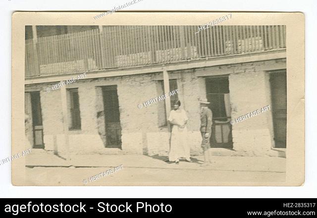 Photograph of a man and woman standing on a sidewalk, early 20th century. Creator: Unknown