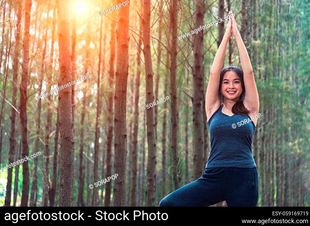 Beautiful happy young female woman relaxation standing outdoor fitness exercise yoga in forest tree nature park with copy space