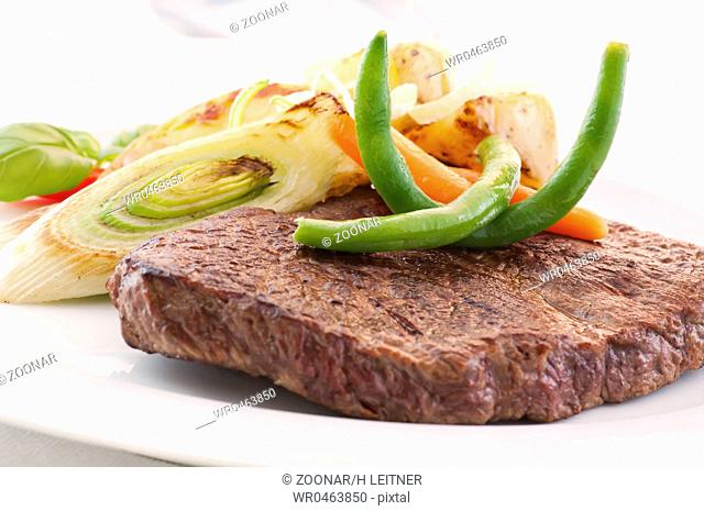 Beefsteak with vegetable as closeup on a white plate