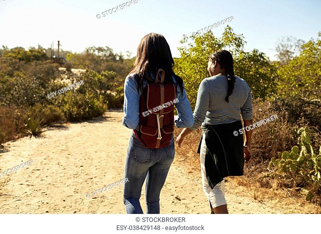 Rear View Of Mother And Adult Daughter Hiking In Countryside