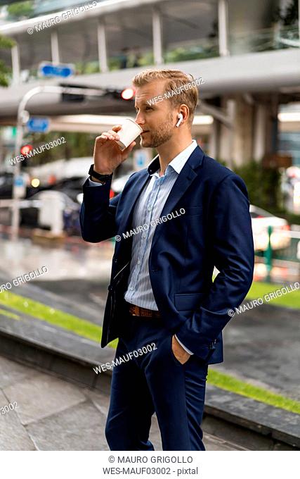 Young businessman with coffee to go in Bangkok during a rainy day