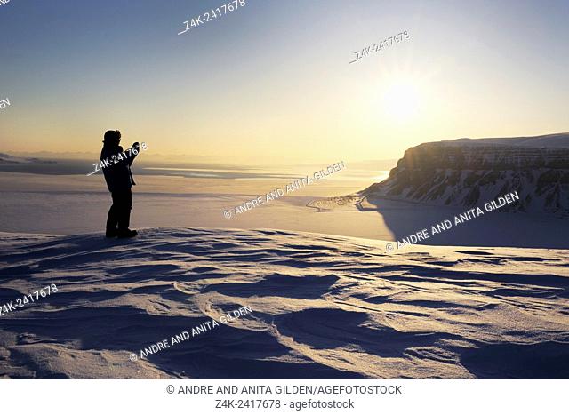 Expedition member looking over the frozen Tempelfjorden at sunset, Spitsbergen (Svalbard)