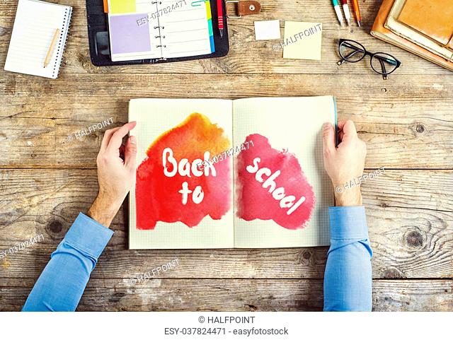Mix of office supplies and Back to school sign on a wooden desk background. View from above