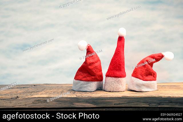 Three hat of Santa on a wooden board with space for text