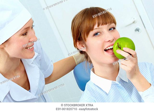 Portrait of pretty woman eating a green apple with nurse near by