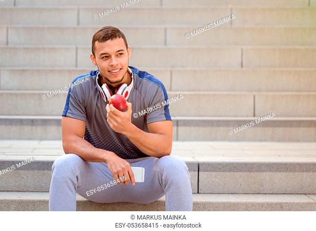 Young man eating apple fruit runner smiling copyspace copy space sports training fitness outdoor