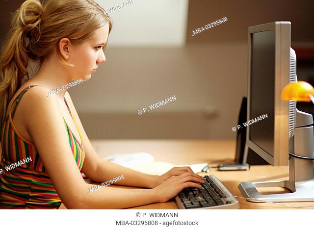 Teenager girl learns half-heartedly home for the school on the computer