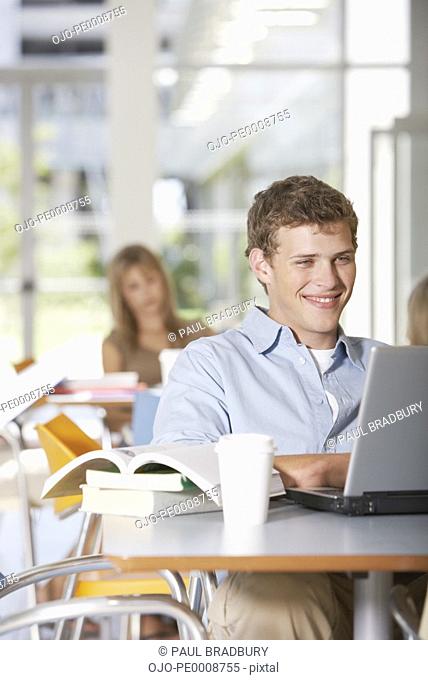 Teenage boy at school with laptop smiling