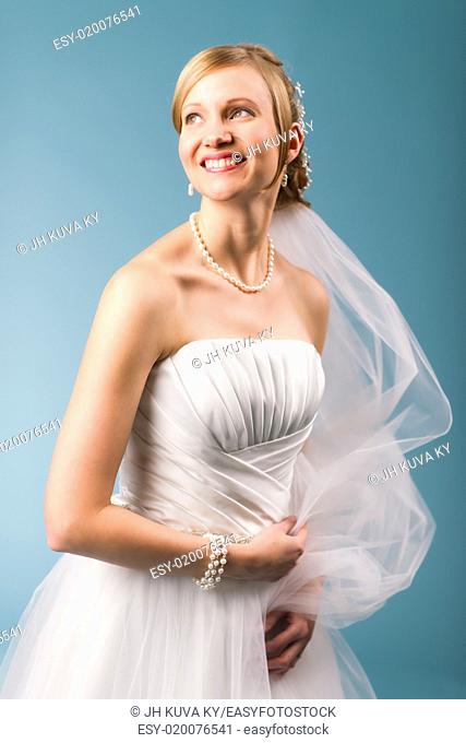 Beautiful bride wearing white wedding dress, blue background
