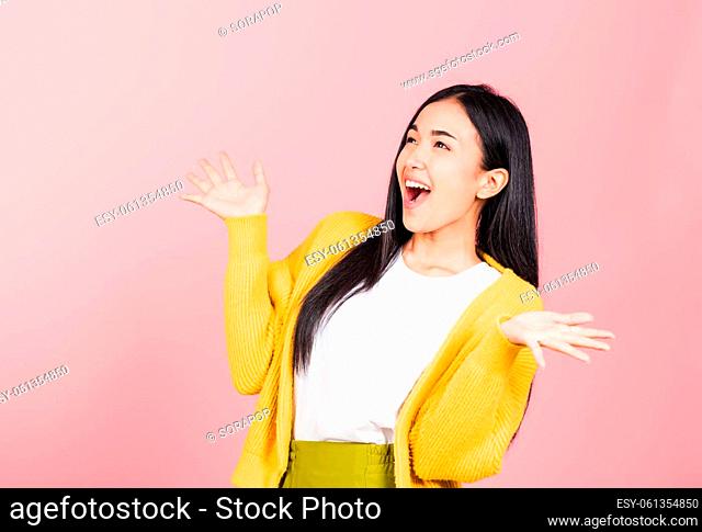 Happy Asian portrait beautiful cute young woman standing winning and surprised excited screaming open mouth raise hands, studio shot isolated pink background