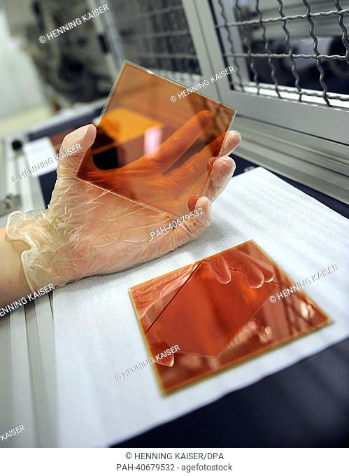An employee of the Fraunhofer institute for solar energy systems holds a glass plate with a silicium layer in her hands in Gelsenkirchen, Germany, 26 June 2013