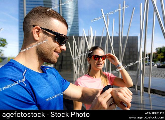 Male athlete adjusting wristwatch on sunny day