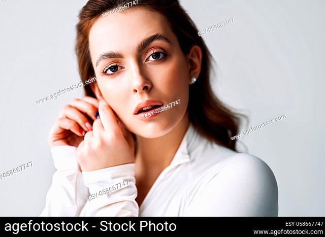 Close up portrait of sensual pretty young woman. Beautiful female model in white cloth with clean skin and sable style eyebrows posing in studio