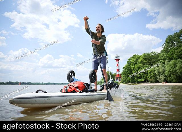 PRODUCTION - 14 June 2023, Hamburg: Christo Foerster, author, filmmaker and micro-adventurer, stands on his SUP on the Elbe River at Wittenbergen beach during a...