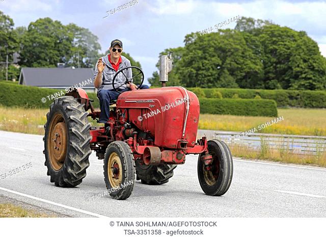 Kimito, Finland. July 6, 2019. Young man greets as he drives classic Porsche-Diesel Super Tractor on Kimito Traktorkavalkad, vintage tractor parade