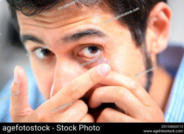 Man putting on contact lens in ophthalmology clinic