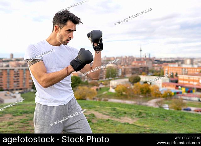 Male acrobat practicing boxing on hill in city