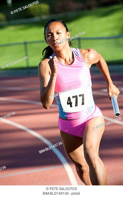Female relay runner running with baton