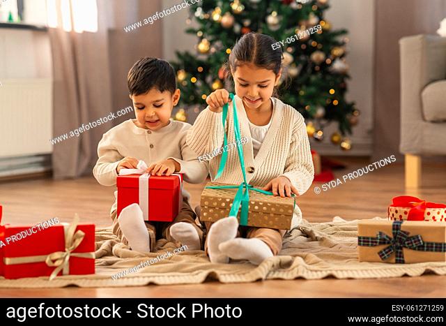happy children opening christmas gifts at home