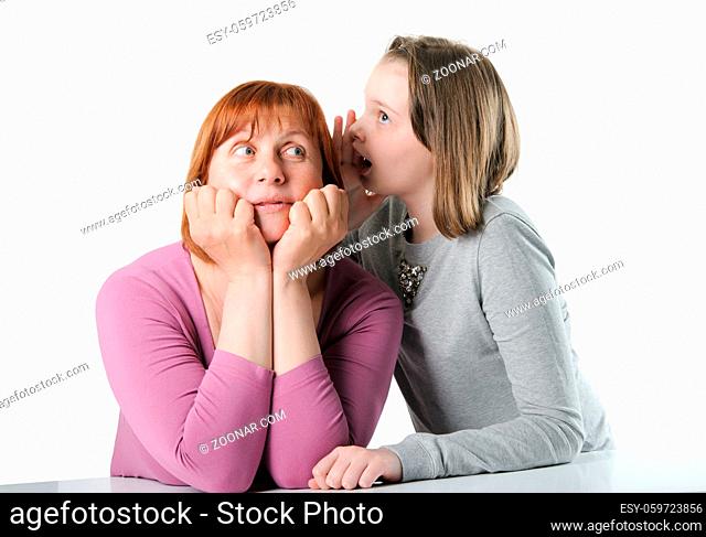 The girl enthusiastically tells something in the ear of her mother